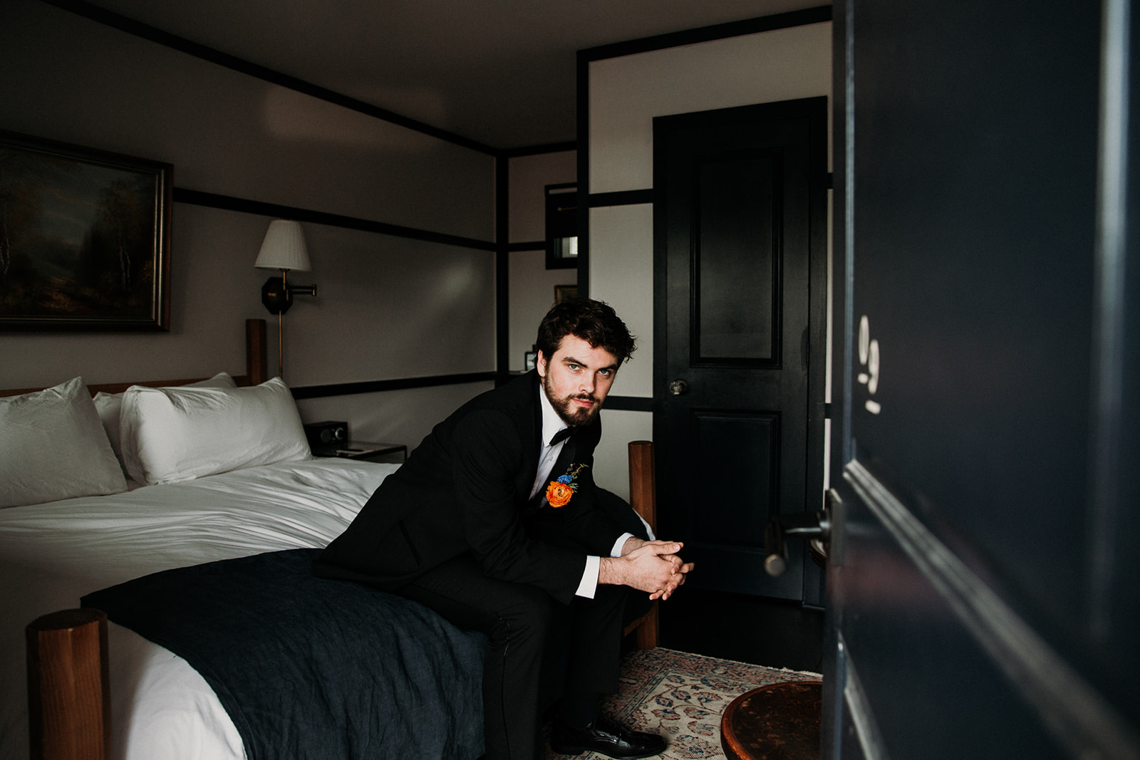 Groom in suit sitting on a bed